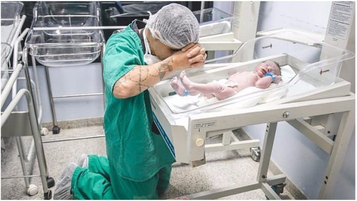 Mladi otac pao na koljena u molitvi pred novorođenim sinom