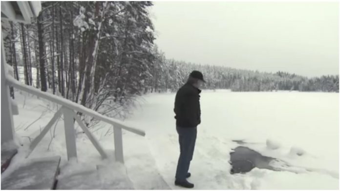 Stariji muškarac pored smrznutog jezera